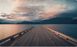 photo of a brown wooden dock in the lake under a cloudy sky during daytime